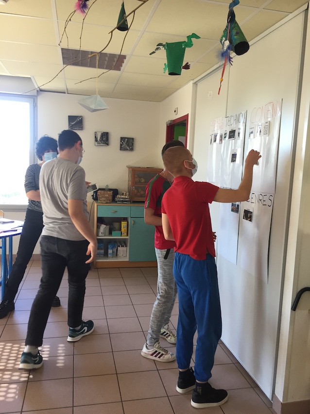 Plusieurs adolescents participent à une animation en observant des affiches installées aux murs.